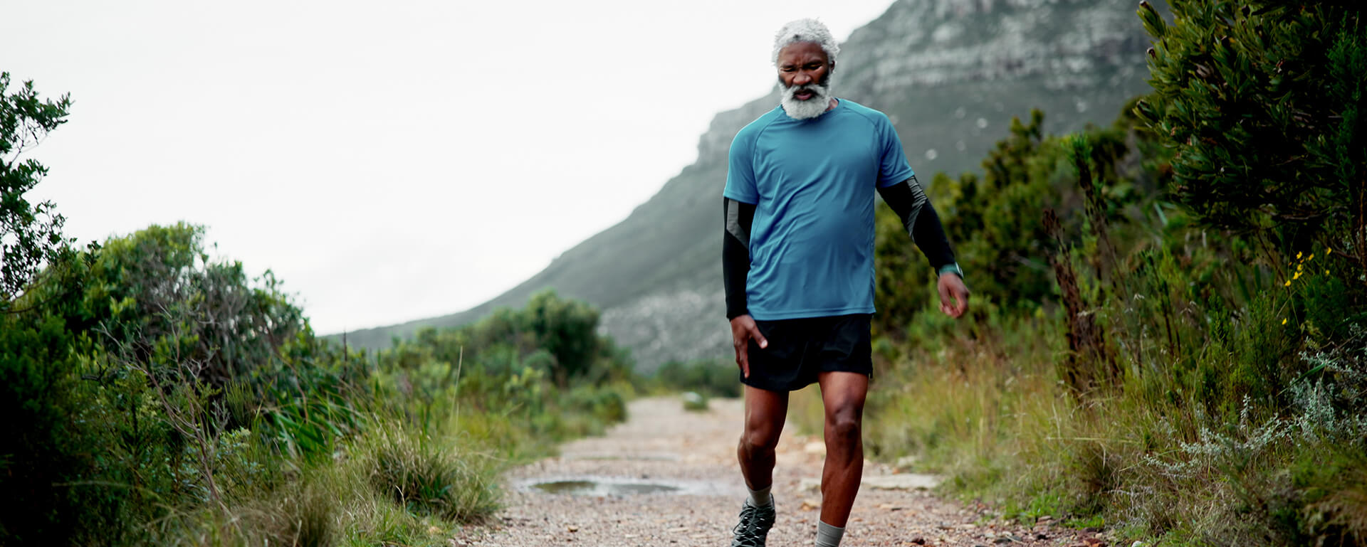 An older man walking on a mountain trail